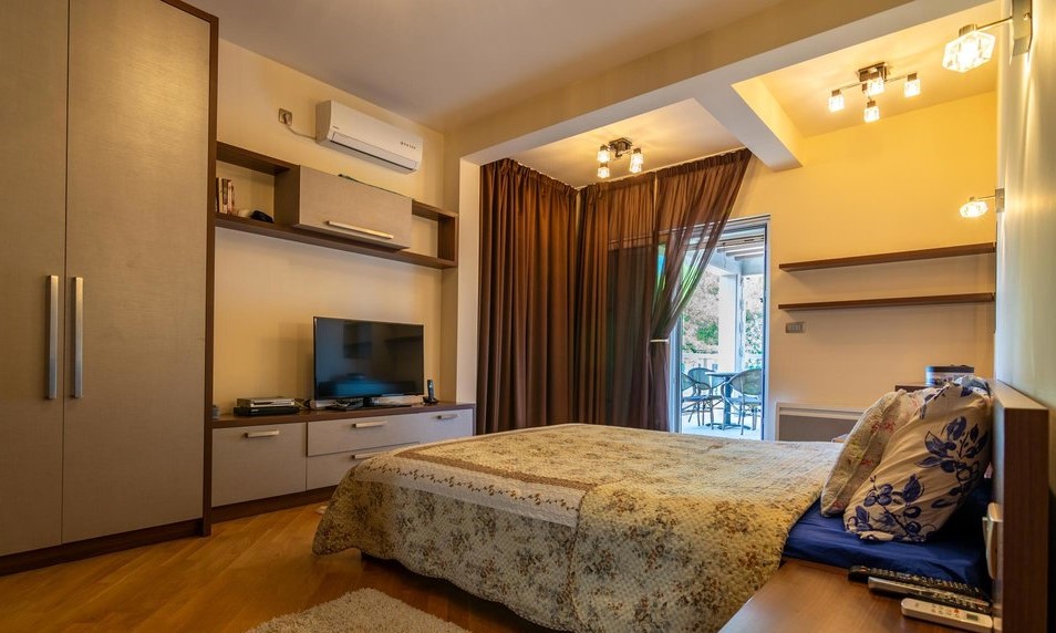 Cozy bedroom with a double bed and access to the terrace in a villa, Tivat, Montenegro. Modern furniture and TV.