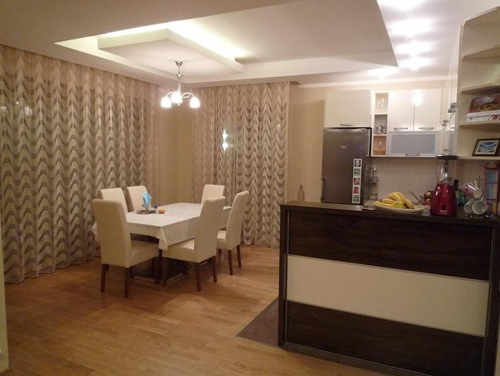Modern living room with dining area in a house in Zelenika, Montenegro: light furniture, a breakfast bar, and panoramic curtains.