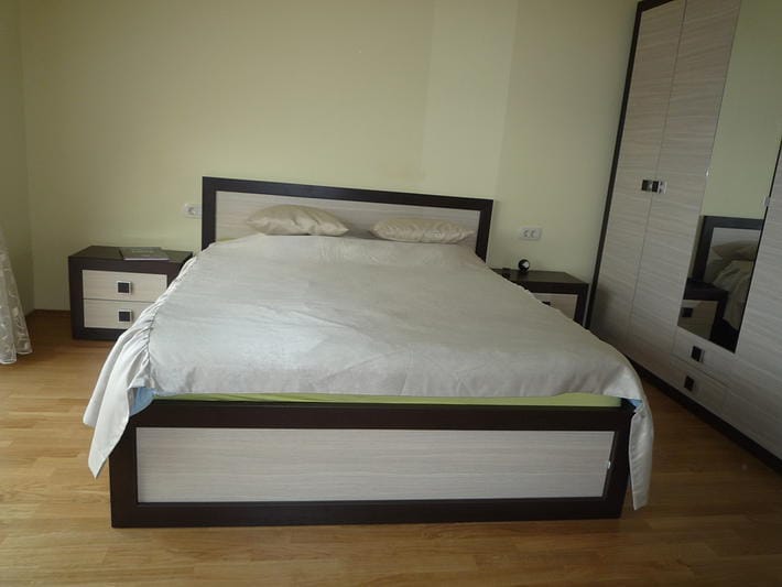 Bedroom with a double bed and wardrobe in a house for sale, Zelenika, Montenegro: bright interior with parquet flooring.