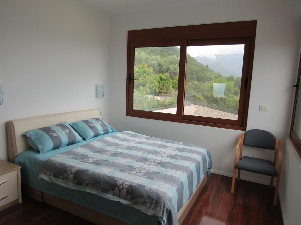 Bedroom in a house in Shushan, Bar Riviera, Montenegro: double bed, wooden floor, and mountain view from the window.