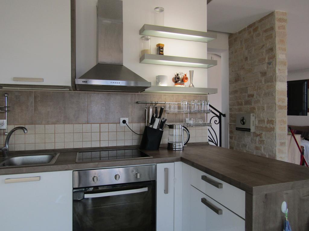 Modern kitchen in a house in Šušanj, Bar Riviera, Montenegro: white cabinetry, stone finishes, and built-in appliances.