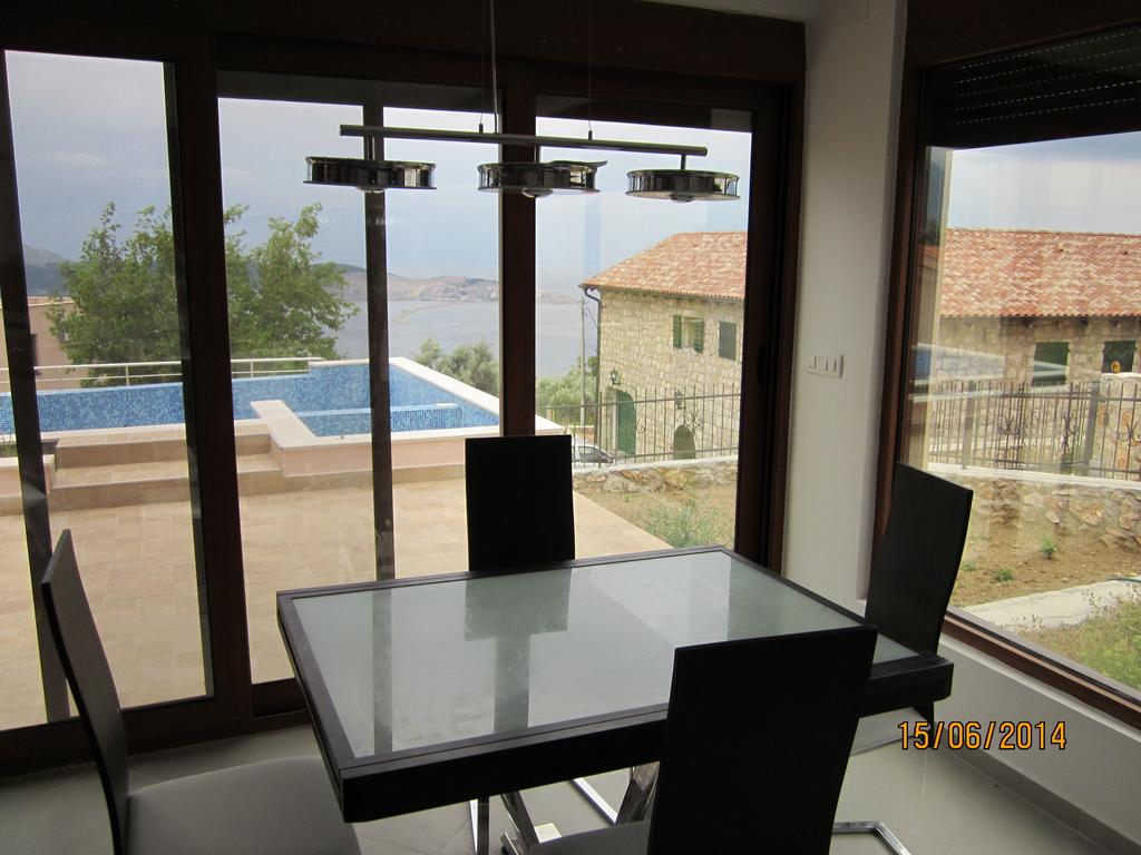 Living room with panoramic windows, dining table, and view of the pool and sea in a house, Bar Riviera, Montenegro.