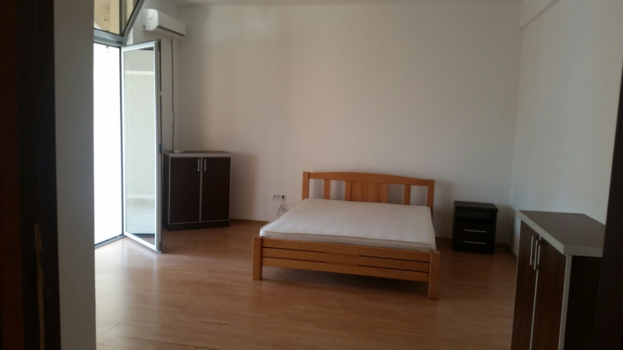 Bright bedroom with a wooden bed and access to the balcony in an apartment, Budva, Montenegro.