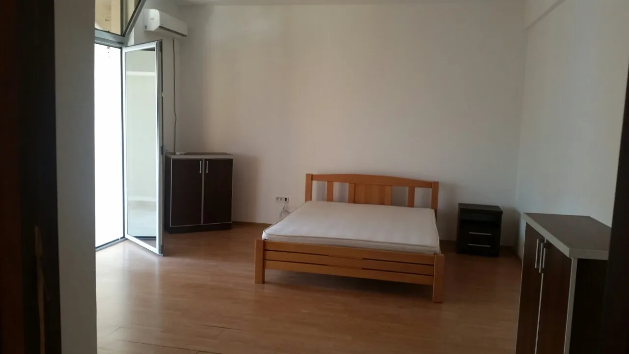 Bedroom featuring a wooden bed frame with mattress, dark cabinets, and a wall-mounted air conditioner.