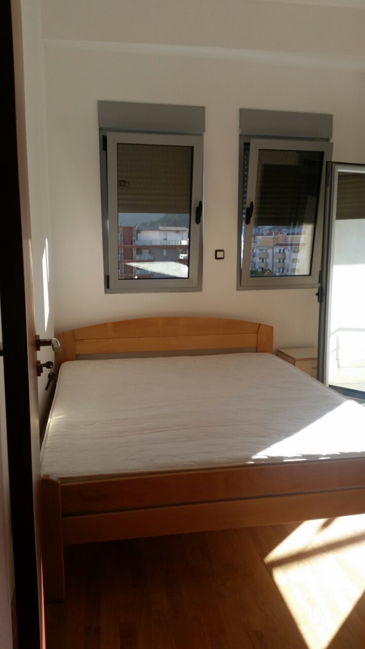 Bright bedroom with a double bed in an apartment in Budva, Montenegro, with access to the balcony and a city view.