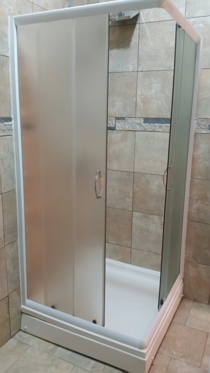 Modern shower cabin in the bathroom of an apartment in Budva, Montenegro, with beige tiled wall finishes.
