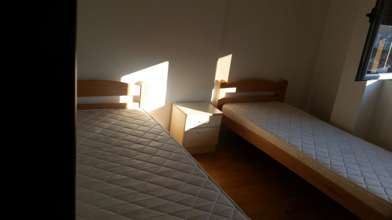 Bright bedroom with two single beds and a bedside table in an apartment, Budva, Montenegro.