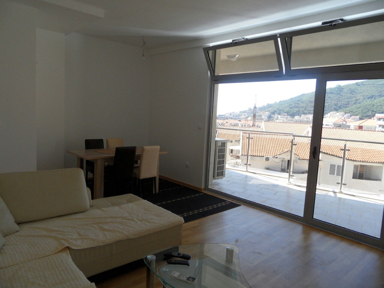 Living room with a panoramic window and access to the terrace in an apartment in Budva, Montenegro: bright interior and mountain view.