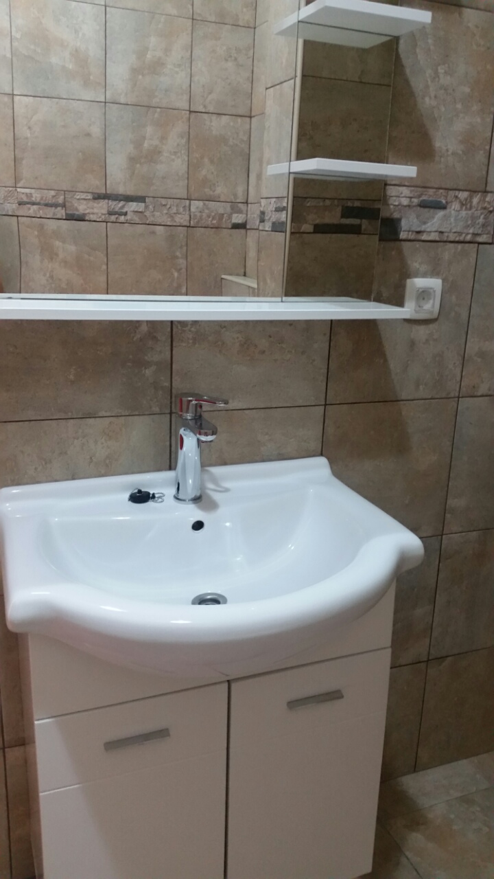 Bathroom in an apartment in Budva, Montenegro: white vanity with sink, chrome faucet, and stone-look tiles.