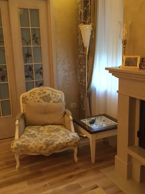 Classic floral armchair, fireplace, and floor lamp in a room corner.