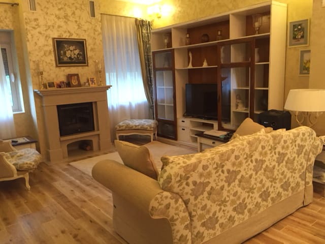 Cozy living room with a fireplace and soft furniture in a house, Zelenika, Montenegro. Classic interior with wooden flooring.