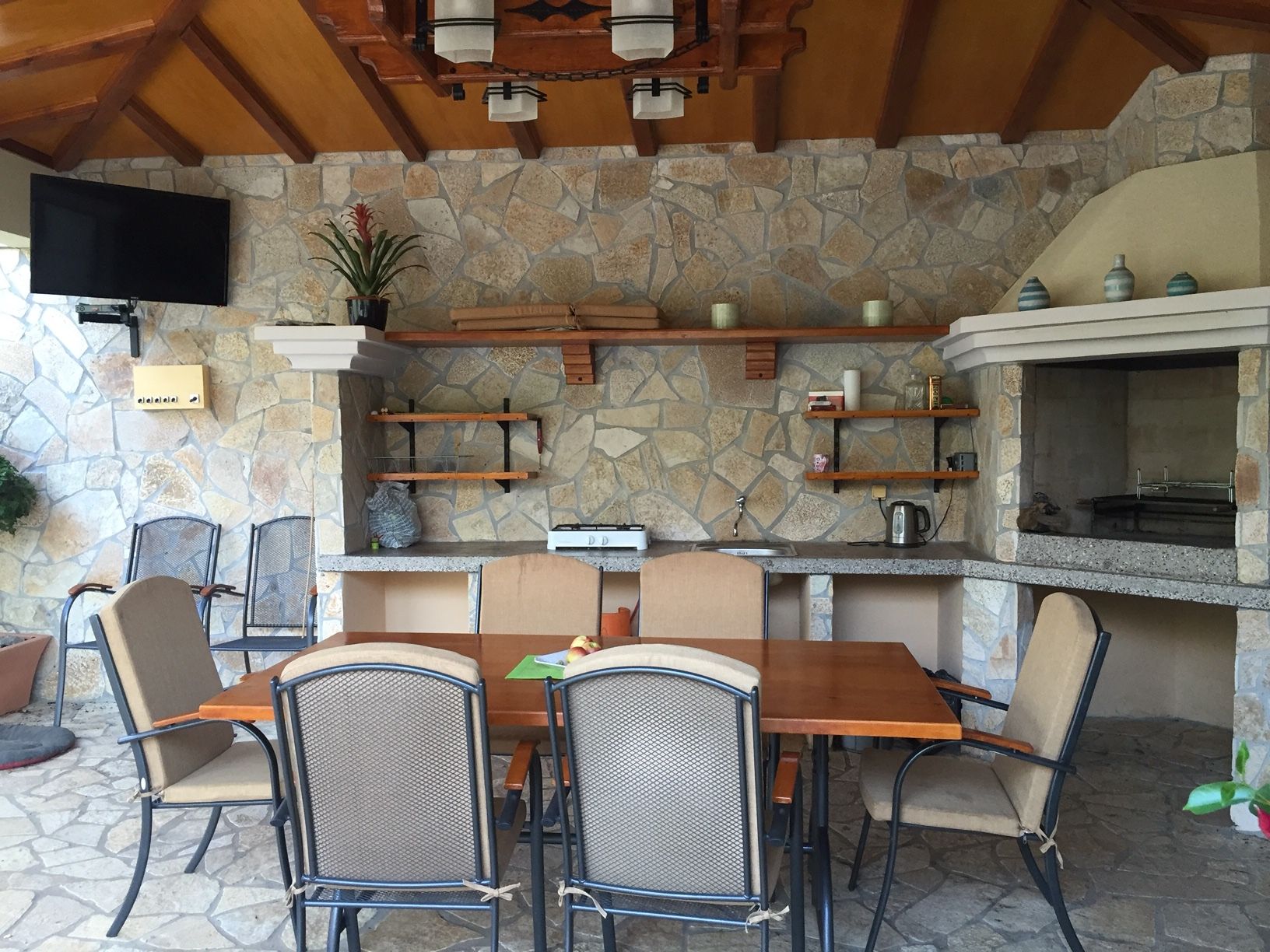 Covered terrace with barbecue, stone finishes, and a dining area in a house in Zelenika, Montenegro.