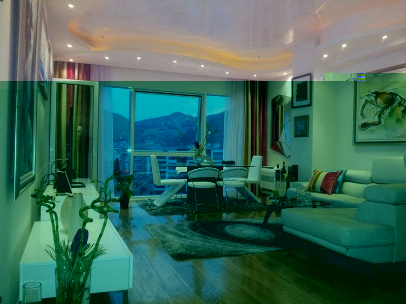 Modern living room in an apartment in Budva, Montenegro: light furniture, panoramic windows with mountain views, and stylish decor.