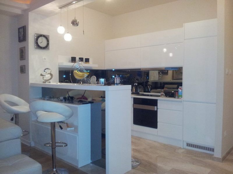 Modern white kitchen with a breakfast bar and built-in appliances in an apartment, Budva, Montenegro.