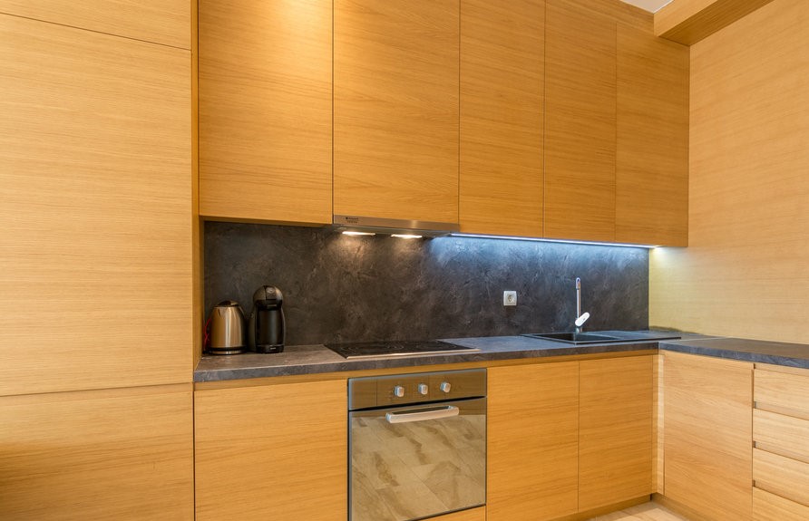 Modern kitchen with wooden фасades and a dark backsplash in an apartment for sale, Budva, Montenegro.