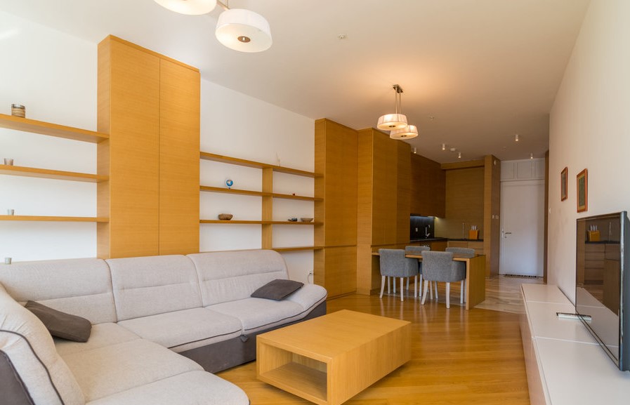 Modern living room with wooden furniture and a light-colored sofa in an apartment in Budva, Montenegro.