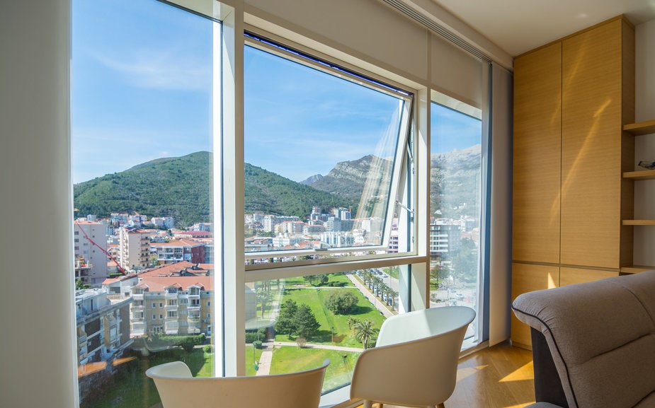 Living room with panoramic windows and a view of the mountains and the city of Budva, Montenegro: modern furniture and a bright interior.