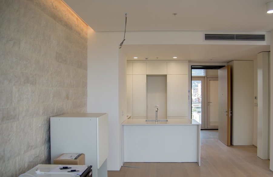 Modern kitchen in an apartment in Budva, Montenegro: bright interior, stone wall, built-in furniture, and island.
