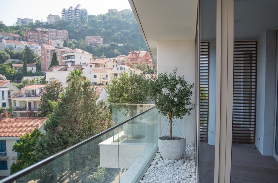 Modern balcony with olive trees and panoramic view of Budva, Montenegro.