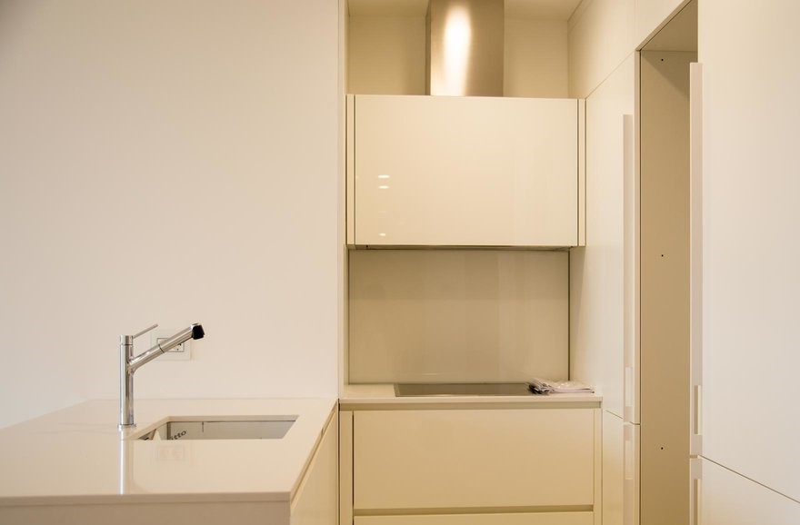 Modern white kitchen with glossy fronts and built-in appliances in an apartment, Budva, Montenegro.