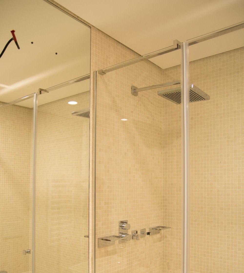 Modern shower cabin with a rain shower and beige mosaic tiles in an apartment, Budva, Montenegro.
