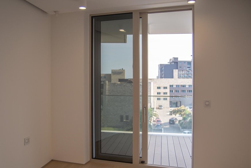 Panoramic window with access to the terrace in a modern apartment in Budva, Montenegro, view of the city and the street.