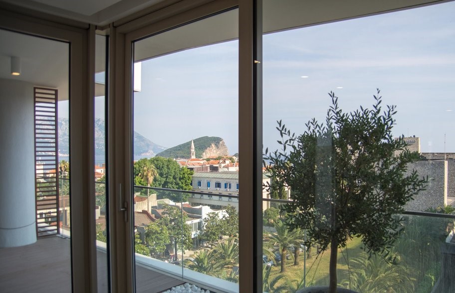View from the panoramic windows of the living room onto the Old Town and the sea in Budva, Montenegro: modern interior and terrace.