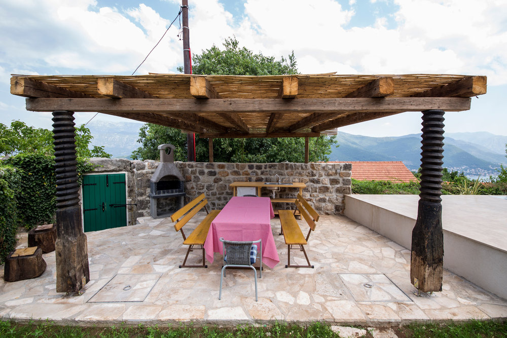 Covered terrace with barbecue and dining area at a villa in Luštica, Montenegro: stone finishes and mountain views.