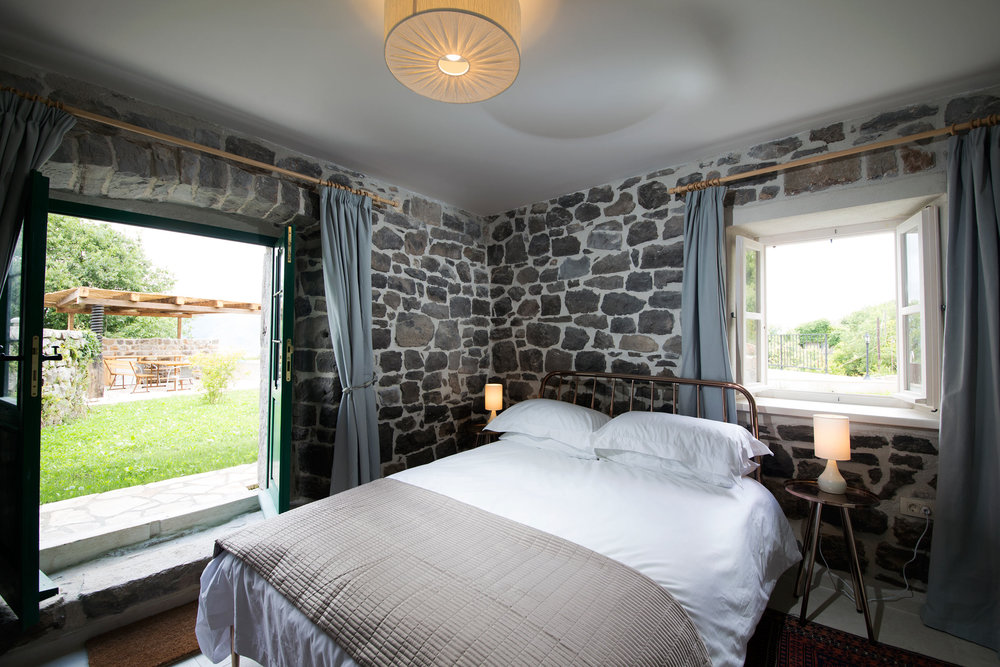 Bedroom in a stone villa on the Luštica Peninsula, Montenegro: double bed, access to the terrace and garden.