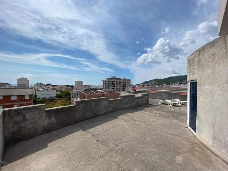 Open terrace with a view of the city and mountains in a house in Shushan, Montenegro, with sun loungers and a concrete railing.