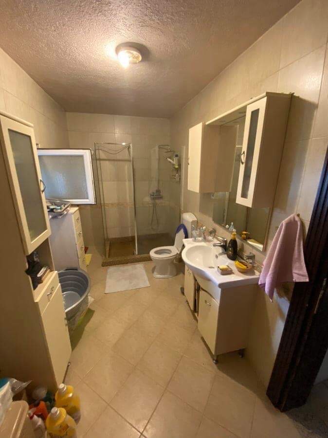 Bathroom in a house in Šušanj, Montenegro: light tiles, shower cabin, vanity with sink, and mirrored cabinet.
