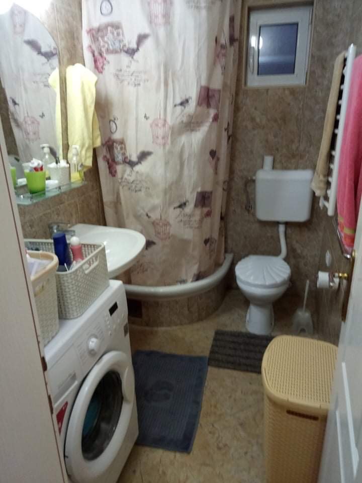 Bathroom in a house in Šušanj, Montenegro: shower cabin, washing machine, plumbing fixtures, and tiled finish.