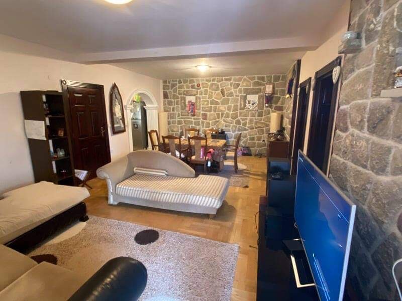 Living room in a house in Shushan, Montenegro: stone wall finishes, upholstered furniture, dining area, and TV area.
