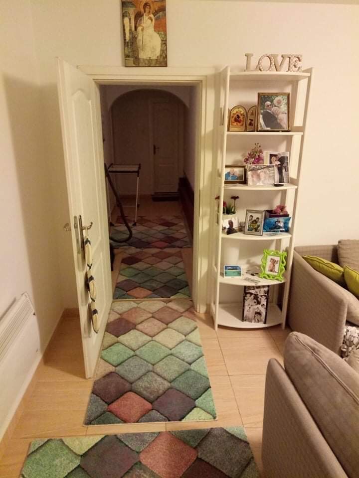 Living room interior in a house in Shushan, Montenegro: light-colored furniture, a shelving unit with decor, and geometric-patterned rugs.