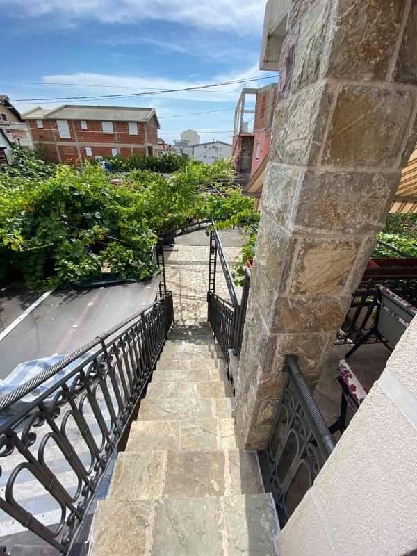 Stone staircase with wrought-iron railings and a view of the green garden by the house in Šušanj, Montenegro.