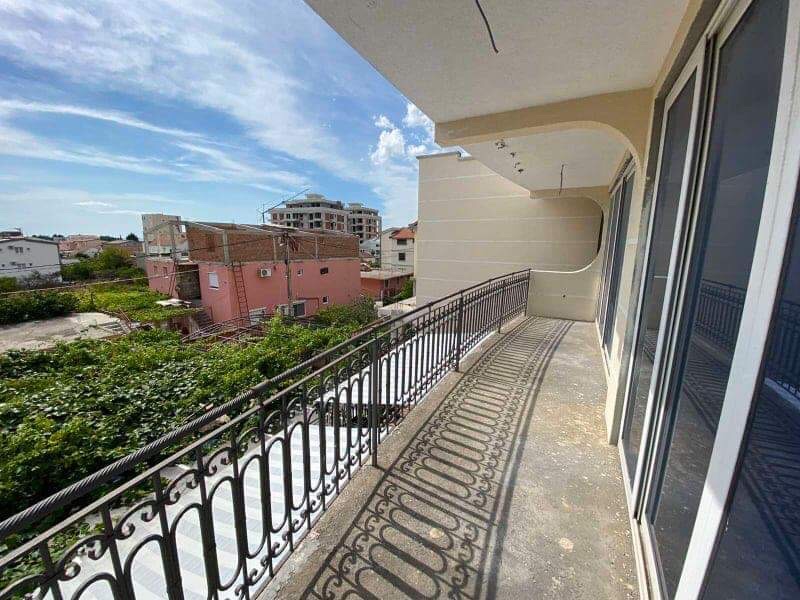 Spacious balcony with wrought-iron railing in a house in Šušanj, Montenegro, overlooking the city and green area.