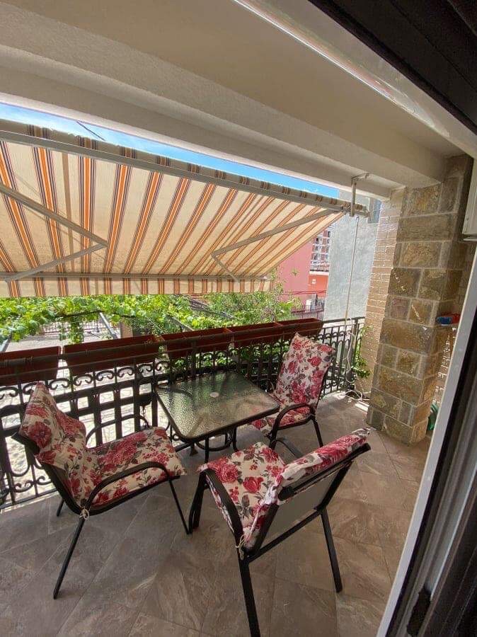 Cozy balcony with garden furniture and an awning in a house in Šušanj, Montenegro: view of the terrace with stone finish.
