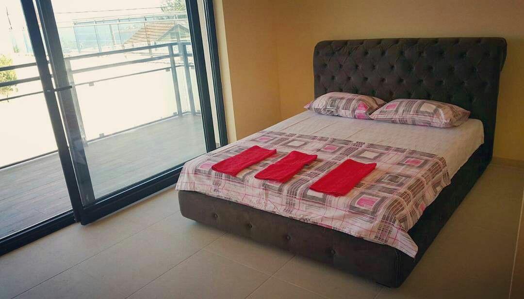 Bedroom with a double bed and access to the balcony in a house, Shushan, Montenegro. Modern interior with panoramic windows.