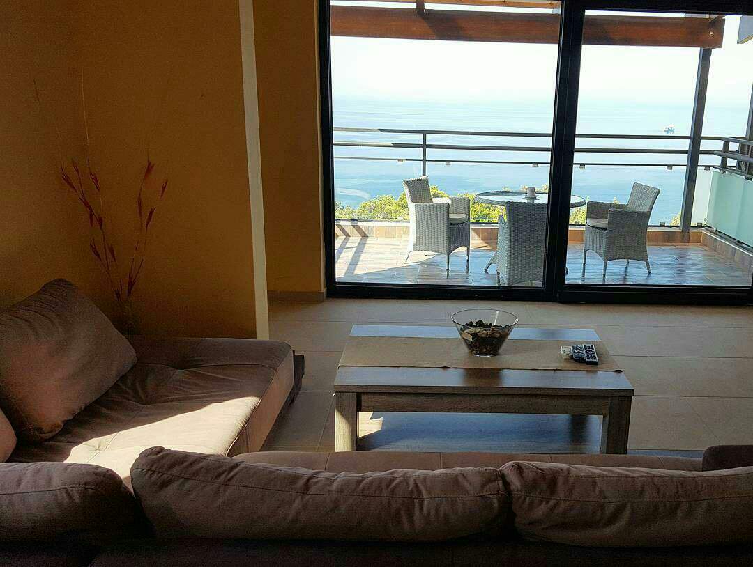 Living room with panoramic sea view and terrace in a house in Šušanj, Montenegro: a soft sofa and coffee table.