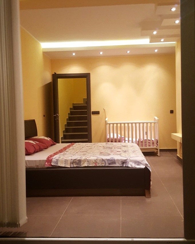Bedroom in a house in Šušanj, Montenegro: double bed, crib, modern lighting, and staircase.