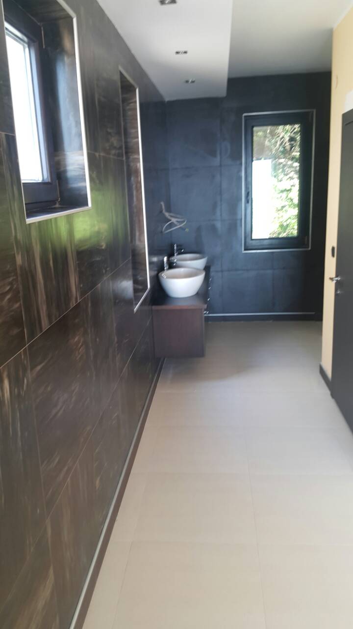 Modern bathroom with dark finishes and two sinks in a house for sale, Shushan, Montenegro.