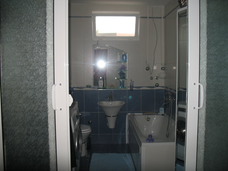 Bathroom in a house in Šušanj, Montenegro: blue tiles, bathtub, sink, mirror, and washing machine.