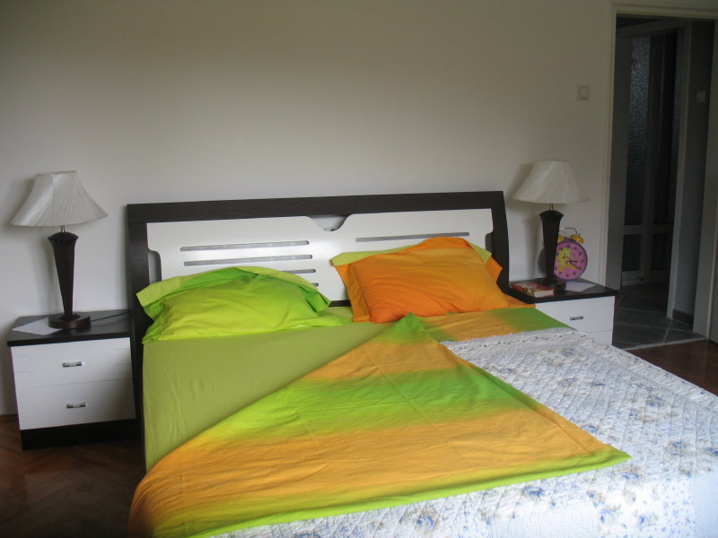 Bedroom in a house in Shushan, Montenegro: a double bed with bright bedding and bedside tables with lamps.