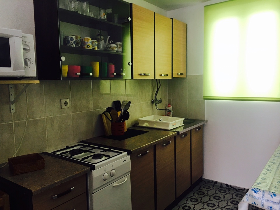 Kitchen with a gas stove and wooden cabinets in a house for sale, Shushan, Montenegro. Interior with tiled flooring.