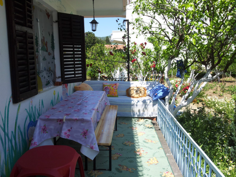 A cozy terrace with garden furniture and a view of the green garden in a house in Šušanj, Montenegro.