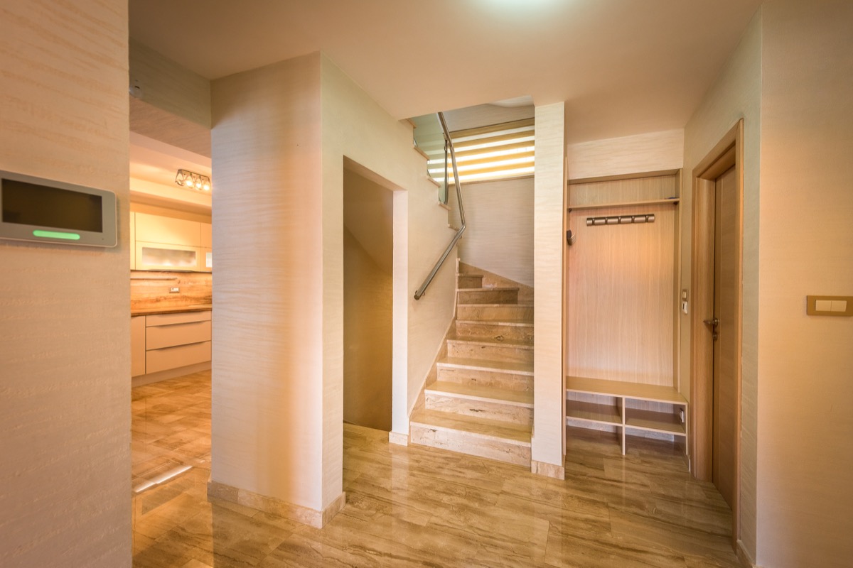 Entrance hall of a villa in Krašići, Montenegro: stone staircase, built-in furniture, and a view of the modern kitchen.