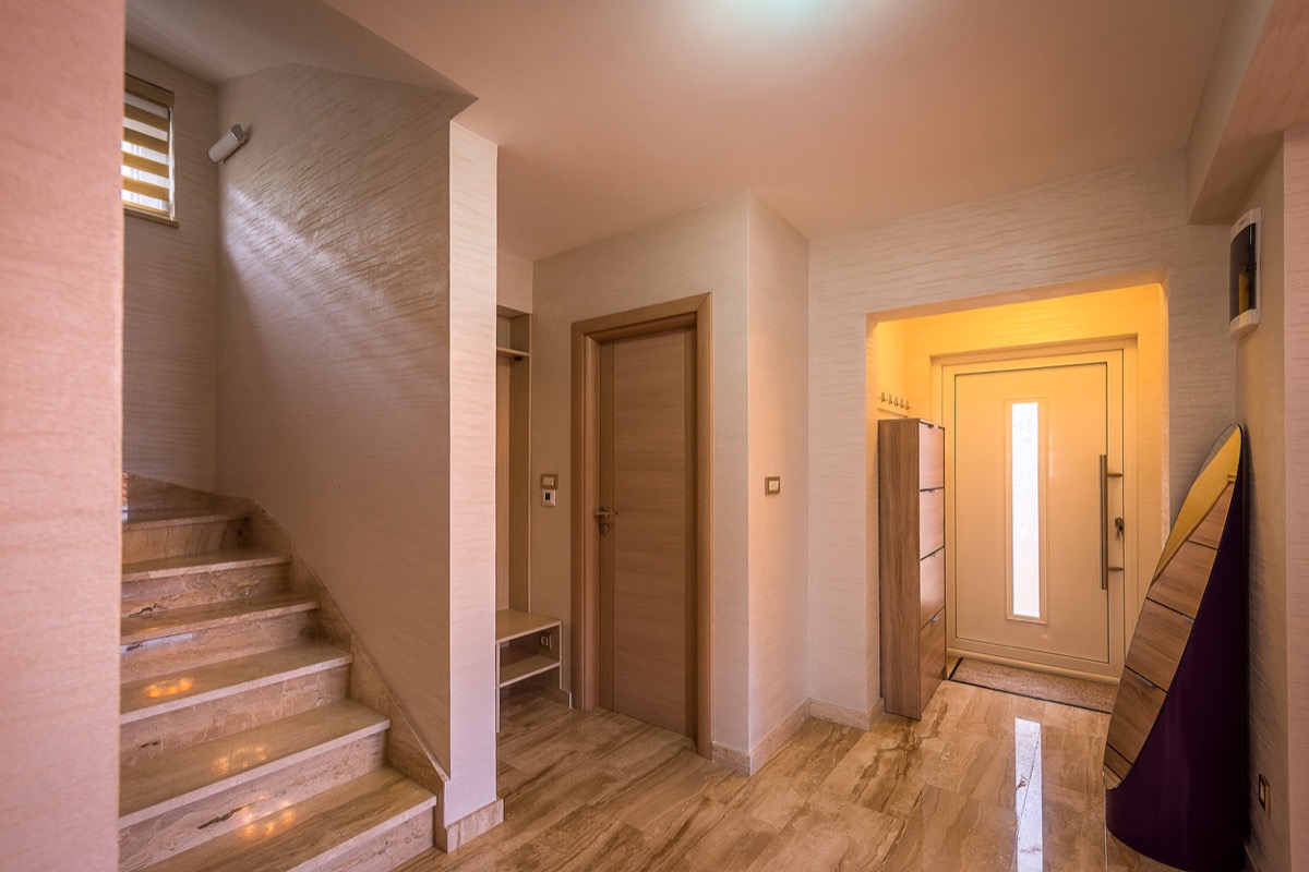 Entrance hall of a villa in Krašići, Montenegro: marble staircase, light-colored wall finishes, front door, and modern furniture.