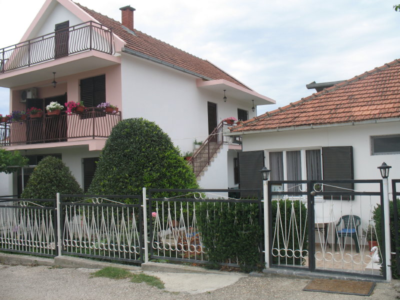 Two-story house with terraces and a garden in Šušanj, Montenegro: view of the facade, fenced grounds, and entrance area.