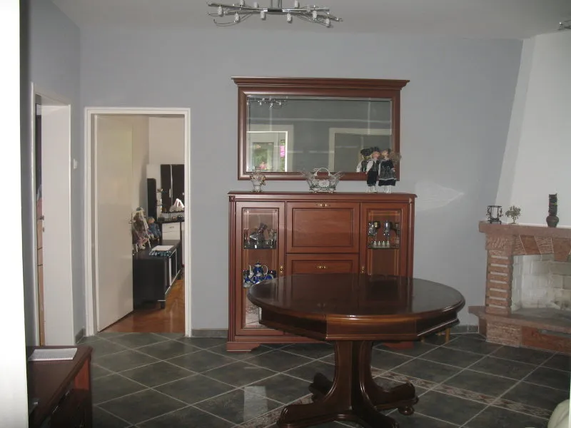 Living room with wooden sideboard, round table, and brick fireplace against a gray wall.
