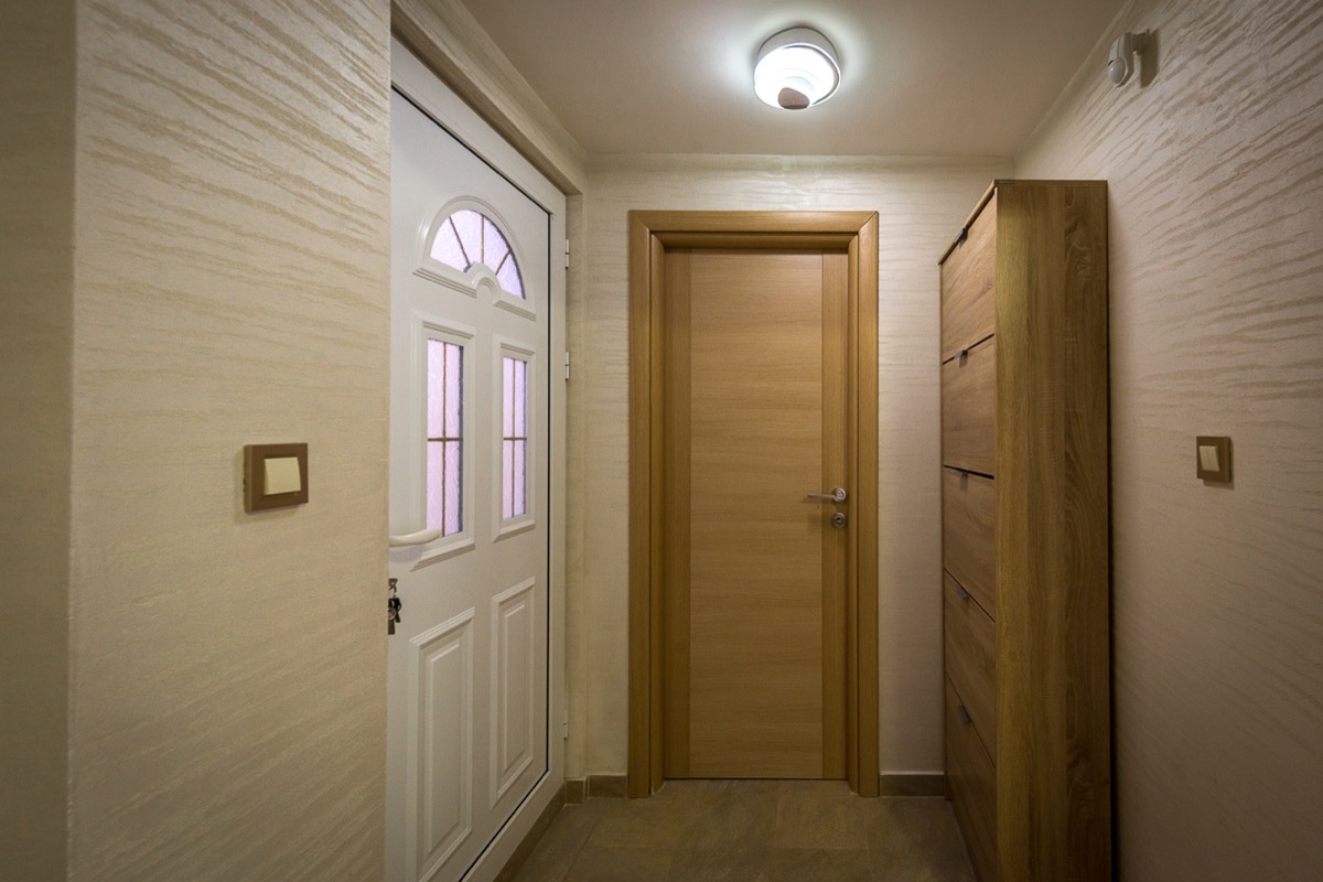 Bright villa hallway in Krašići, Montenegro: white front door, interior door, and wood-finish wardrobe.